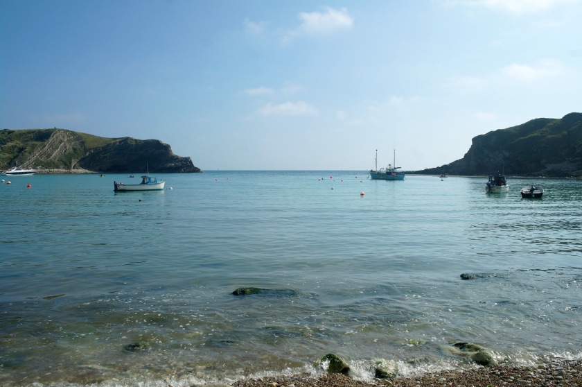 Looking out across Lulworth Cove, Dorset, England. Boats in Lulworth Cove on a sunny September day.
